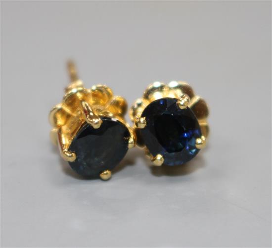 A pair of yellow metal (stamped 18k) and solitaire oval cut sapphire set eat studs, sapphires approximately 4.5mm in length,